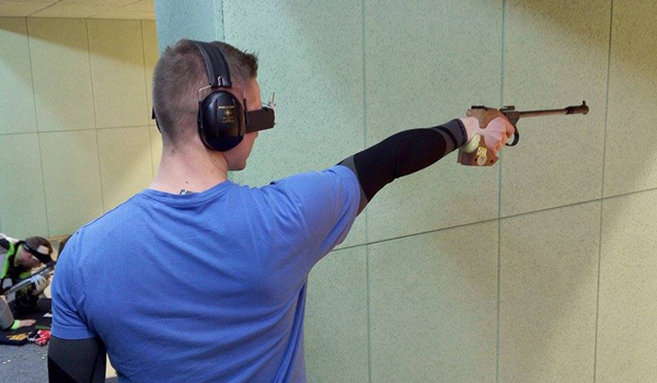 Młody mężczyzna strzela z pistoletu sportowego
