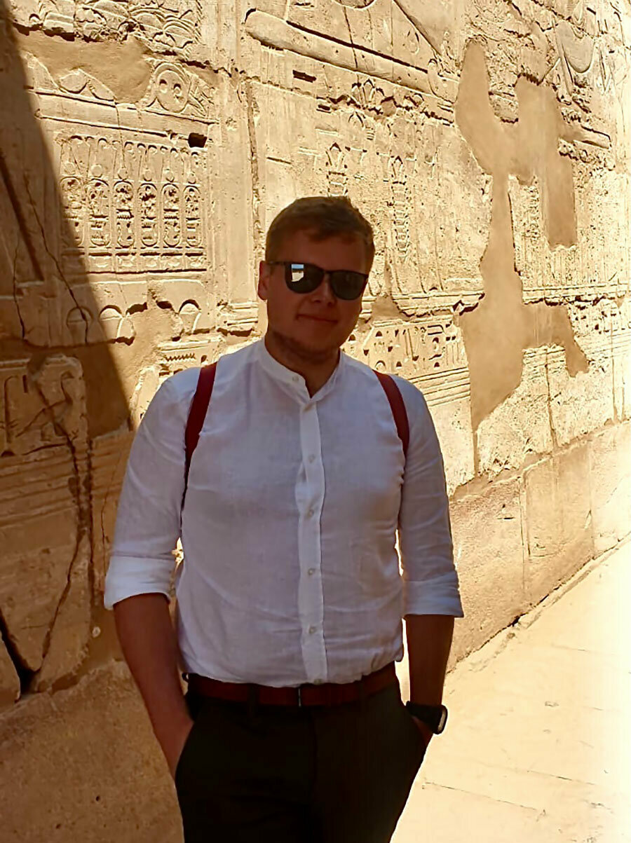 Mateusz Szołdra na tle muru z egipskimi hieroglifami