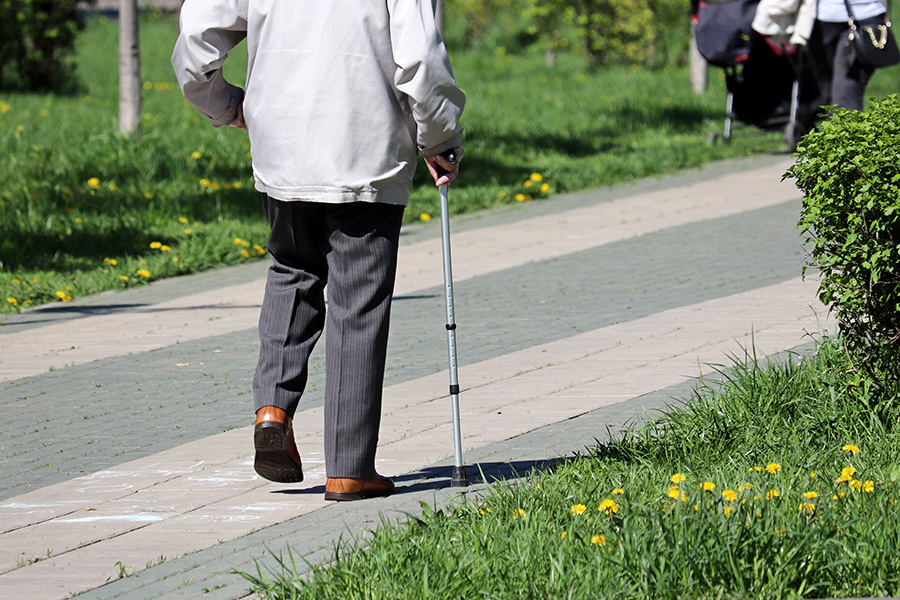 starsza osoba idzie po chodniku